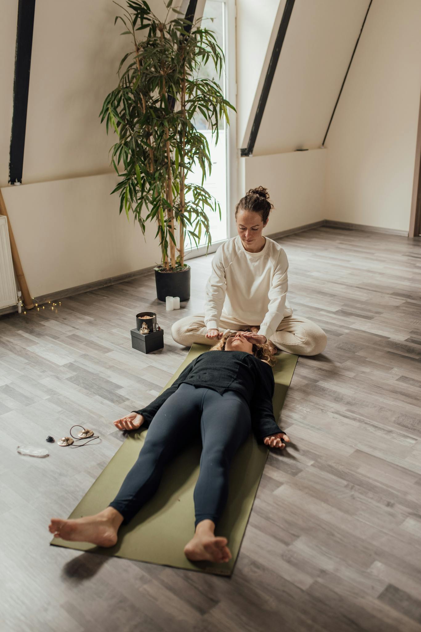 A soothing therapy session indoors with a person relaxing on a yoga mat, guided by a therapist.